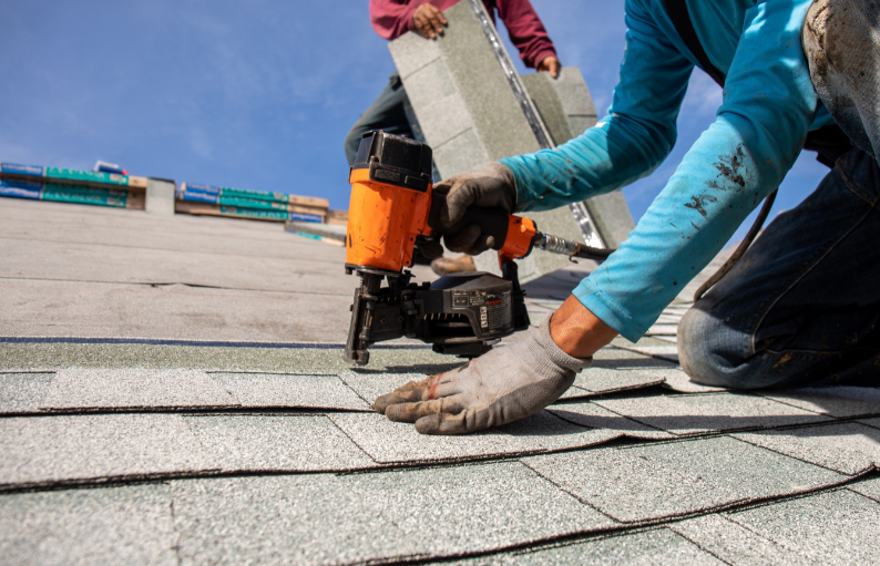 Two roofers installing roof shingles